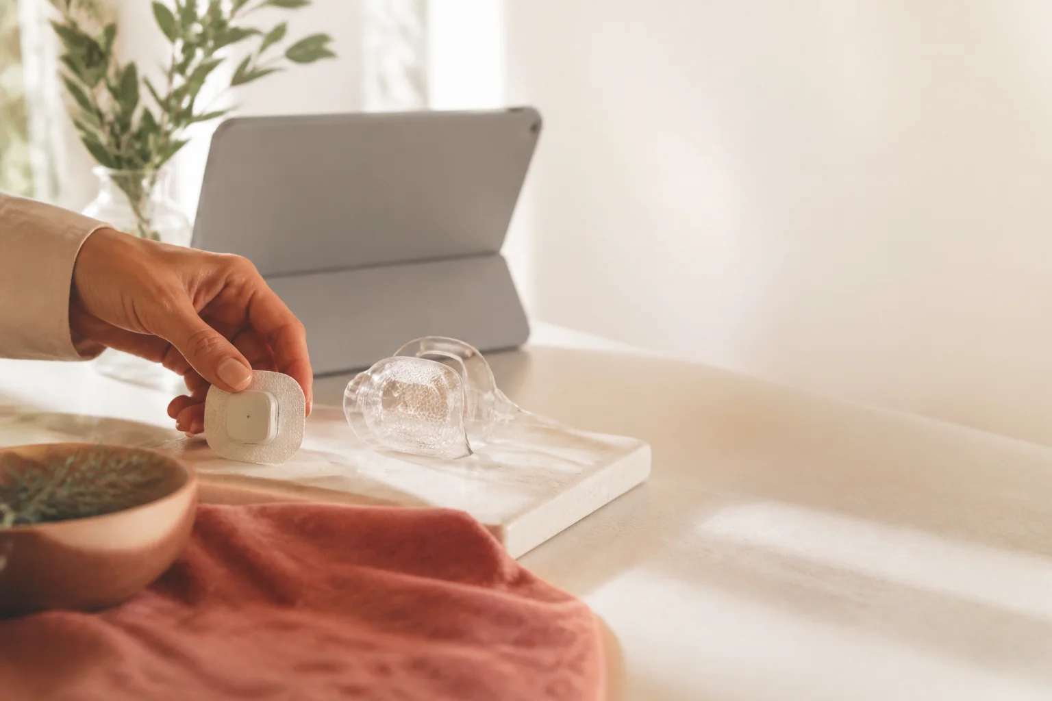 A hand arranging a connected health sensor in a sunlit studio